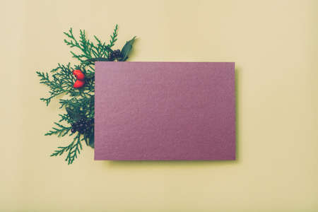 Festive greeting card. Purple mockup paper sheet with green juniper sprig and fall berries decor on...