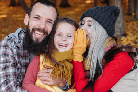 Autumn nature park. Joyful young parents and their daughter having fun in fall forest. Foliage background.の写真素材