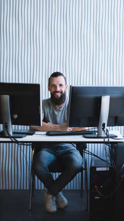 Successful business project. Happy male engineer sitting at his workplace, smiling. Copy space.