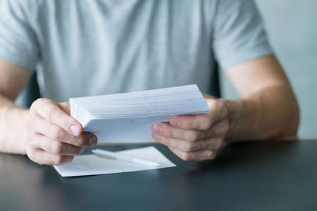 Paperwork and sending mail. Cropped shot of man holding envelopes, writing invitation letters.