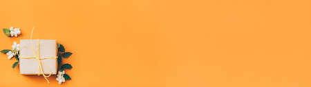 Autumn holiday greeting card. Orange background with beige paper gift box and mistletoe decor. Copy...