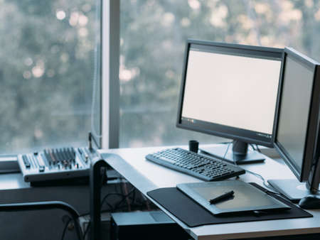 Creative illustrator workplace. Digital art board, stylus, white mockup monitor screen. Blur window background. Copy space.の写真素材