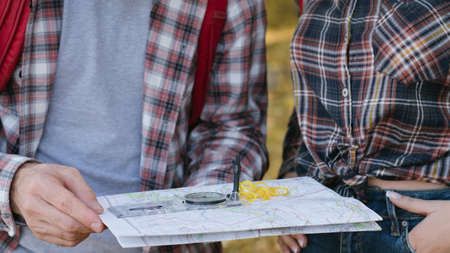 Hiking tourism hobby. Cropped shot of travelers using compass and map to explore country.の写真素材