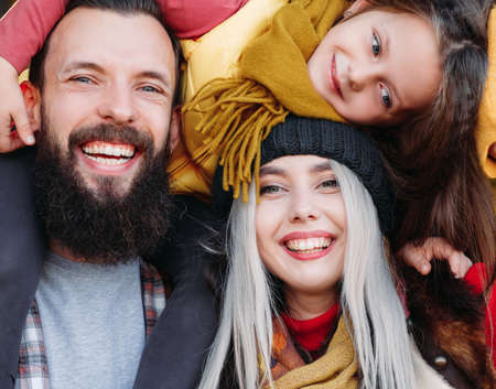 Outdoor family leisure. Closeup of joyful young parents and their daughter having fun together, smiling.の写真素材
