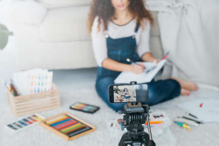 Artist vlog. Creative lady sketching, using smartphone camera to record drawing tutorial video. Blur background.の写真素材