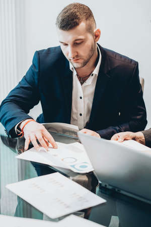 Corporate lifestyle. Confident business man working with papers at desk in conference room.