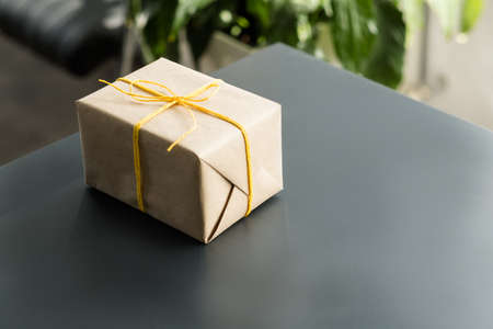 Handmade birthday present. Closeup of beige paper wrapped gift box on office desk. Copy space.