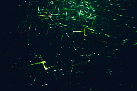 Neon green shiny glitter. Illuminated angled lines and dots. Dark abstract background.
