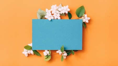 Party invitation. Blue mockup paper sheet with mistletoe decoration on orange background. Copy space.の写真素材