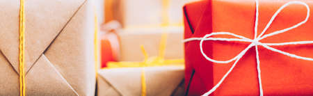 Handmade gift packaging. Cropped closeup of beige and red paper boxes. Blur background. Copy space.