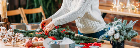 Craft workshop. Cropped shot of female florist using green fir tree twig to create Christmas interior decoration.の写真素材