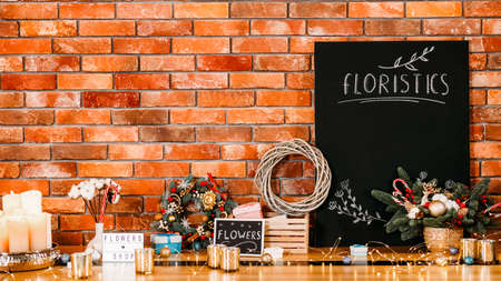 Flowers shop. Festive gift decoration. Mockup black chalkboard with floristics lettering. Brick wall background. Copy space.の写真素材
