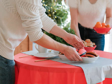 Christmas eve. Cropped shot of couple setting festive table with mandarins and gingerbread cookies in home kitchen.の写真素材