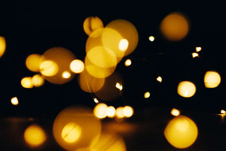 Yellow lens flare. Defocused circle lights. Night party gleam effect. Abstract black background.の写真素材