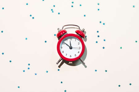 New Year greeting card. Vintage red alarm clock on blue star pattern white background. Copy space.