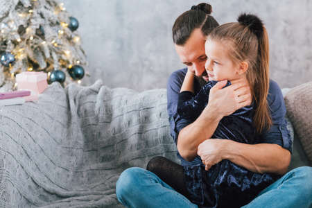 Family home Christmas celebration. Happy father hugging his cute little daughter, smiling. Copy space.の写真素材