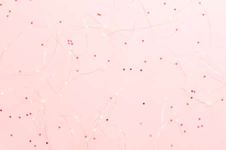 Winter holiday decoration. Top view of warm white LED string lights on star pattern pink background....