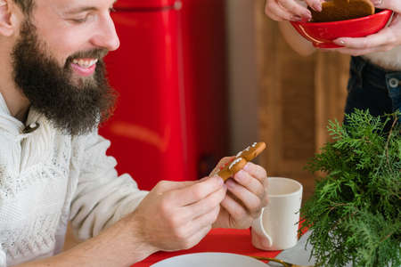Christmas bakery food. Closeup portrait of happy bearded guy holding gingerbread man cookie his wife made, smiling.の写真素材