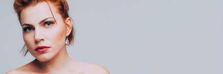 Female beauty. Woman portrait with bare shoulders over gray background. Copy space.