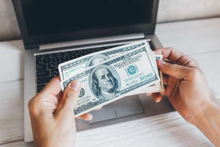 Startup investment. Hundred dollar bills, laptop. Male hands with cash money.