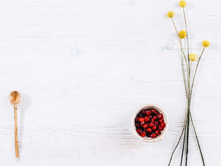 White rustic kitchen background. Red dried fruit, wooden cooking spoon, yellow flowers.の写真素材