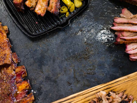 Smoked meat assortment. Cropped top view of sliced beef brisket, pulled pork, ribs arranged as frame. Copy space.の写真素材