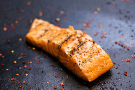 Steakhouse and seafood restaurant. Closeup of juicy piece of smoked salmon fillet with colorful seasoning.の写真素材