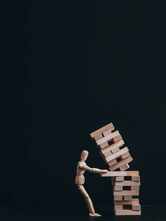 Bad choice. Wrong decision failure. Articulated manikin pulling out brick. Falling down construction.の写真素材