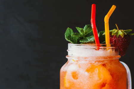 Healthy diet. Homemade lemonade. Peach fresh cold drink with strawberry decor on dark background.