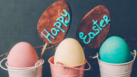 Happy Easter. Holiday food decor. Three pastel painted eggs in buckets two cake pops.の写真素材