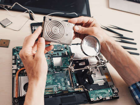 Computer diagnostics. Hard disk drive, magnifier. Technician examining components.の写真素材
