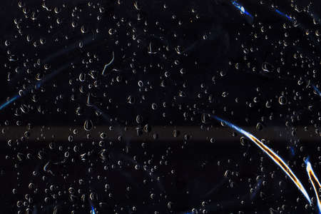Wet abstract background. Dew texture. Rain drops on blue wrinkled clear plastic surface.