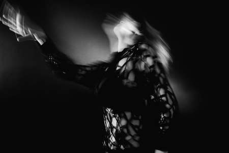 Spiritual dance. Reincarnation freedom. Defocused woman silhouette in transcendent posture on black with blur lights.の写真素材