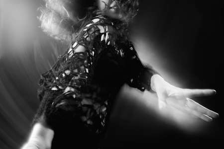 Dancing woman silhouette. Enlightenment energy. Lady in black enjoying freedom on dark with motion...
