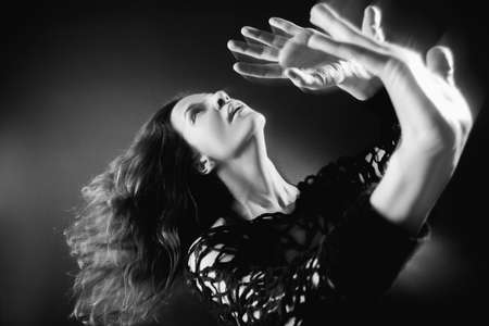 Spiritual practice. Soul healing. Inspired woman enjoying transcendent energy on dark with motion...