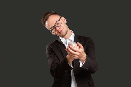 Special gift. Birthday surprise. Happy curious business man holding present in small box with care isolated on black. Holiday congratulation for boss. Festive occasion.の写真素材