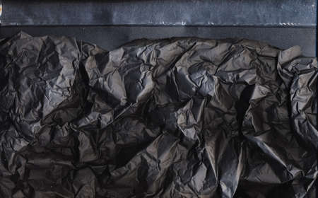 Black crashed foil. Crumpled paper texture. Distressed film structure on dark background.の写真素材
