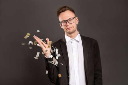 Disappointed birthday guy. Boring party. Annoyed dissatisfied business man throwing confetti isolated on dark. Loser portrait. Ruined celebration. Fake fun.の写真素材