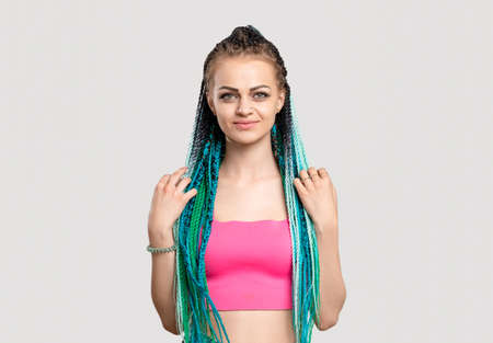Woman with blue braids. Colorful hair. Portrait of cheerful lady in pink top with ethnic hairstyle...