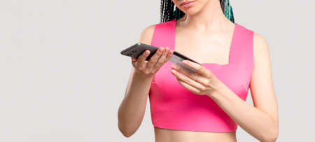 Mobile banking. Online shopping. Millennial woman in pink with blue hair braids paying with credit...
