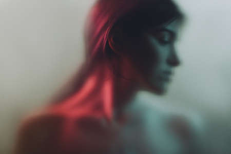 Art portrait. Feminine mystery. Sensual woman blur silhouette in neon red light gray fog with noise effect. Soul freedom. Loneliness contemplation. Subconscious melancholy.の写真素材