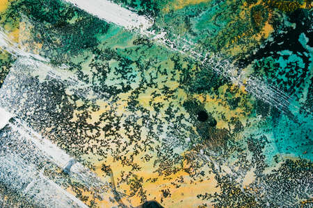 Colorful alcohol ink. Marble texture. Turquoise blue yellow stained surface with white paint strokes water drops streak grain black fleck effect. Mineral stone design art background.の写真素材