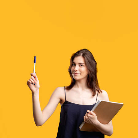 Clever woman with notebook isolated on orange. New decision. Important message. Educational coursesの写真素材