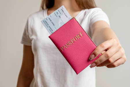 World travel. Global immigration. Woman showing id passport in pink cover American citizen first class flight ticket isolated on blur neutral background. Holiday trip. Airport check-in.の写真素材