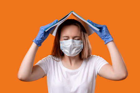 Coronavirus panic. Infection risk. Anxious female student in face mask gloves protecting head...