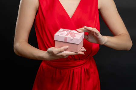 Shopaholic lifestyle. Black Friday. Elegant woman in red cocktail dress holding bunch of colorful shopping bags isolated on dark gray copy space background. Sale discount. Special offer.の写真素材