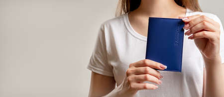 Passport service. Residence permit. Woman in white t-shirt showing national id in blue cover...