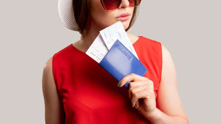 Summer holiday. Travel agency. Woman in red dress holding foreign id with tickets isolated on...