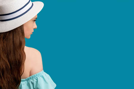 Summer vacation. Holiday outfit. Pretty brunette woman in off-the-shoulder dress and white hat...