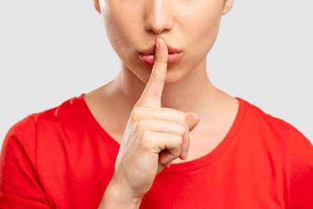 Dislike gesture. Bad job. Sad woman in red t-shirt showing thumb down looking at camera. Isolated on neutral. Disapproval sign. Unhealthy habit. Advertising backgroundの写真素材